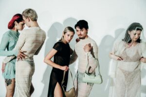 Stylish group portrait featuring models posing in sheer, lace garments against a white background.