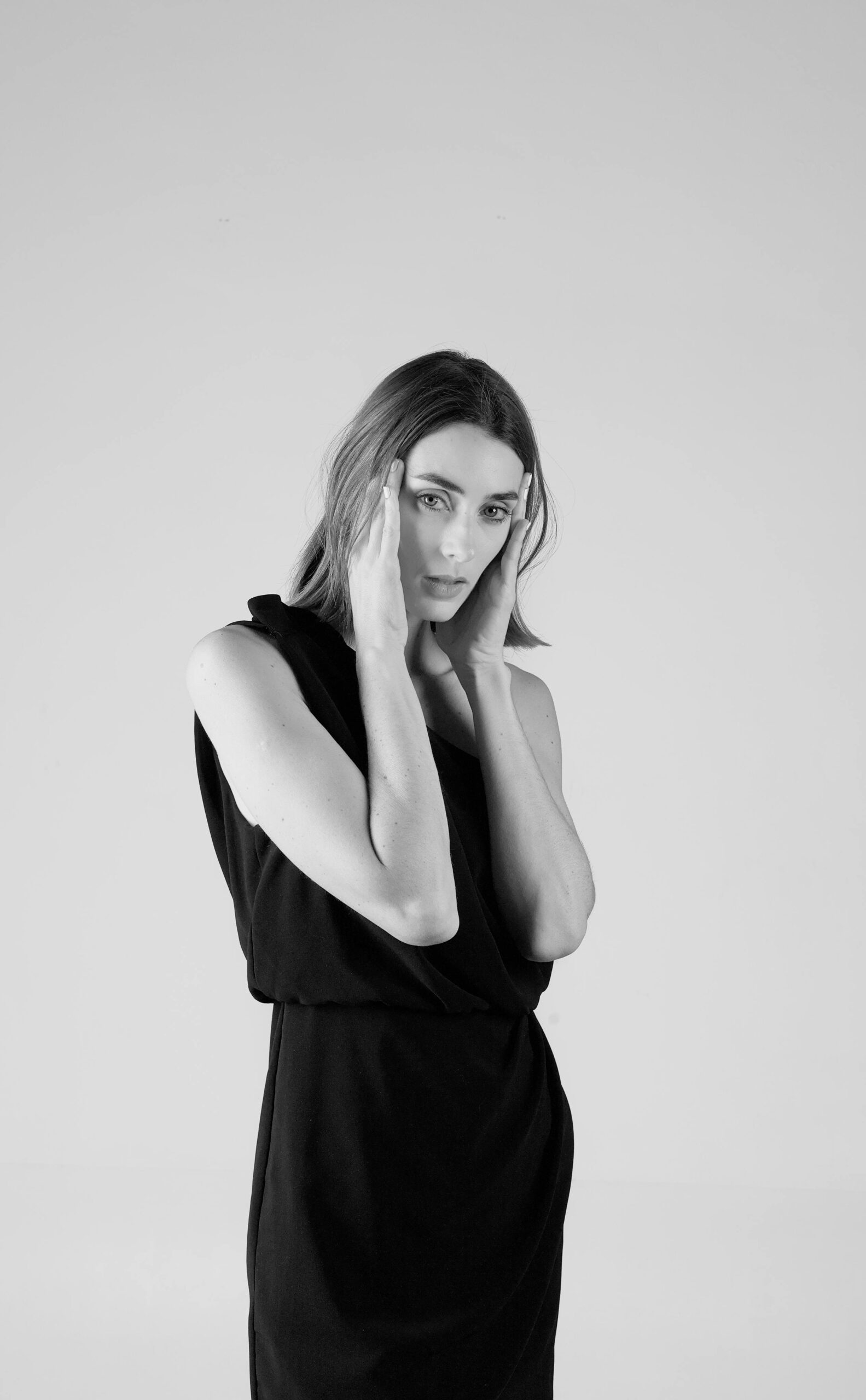 Artistic black and white portrait of a woman in a studio setting, conveying elegance and fashion.