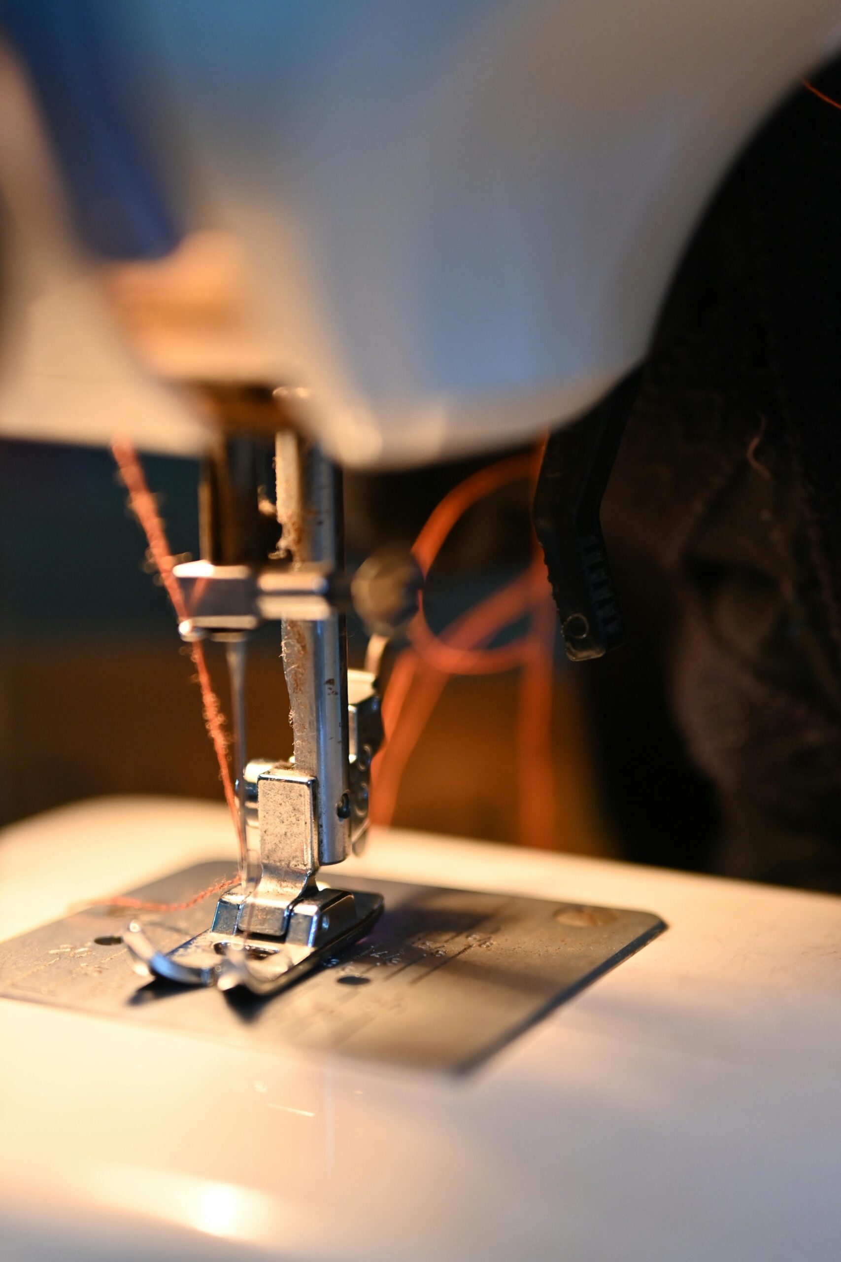 Detailed view of a sewing machine needle threading fabric, capturing the craftsmanship of sewing.